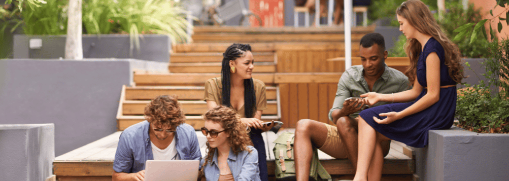 group of young people sitting on benches speaking to each other