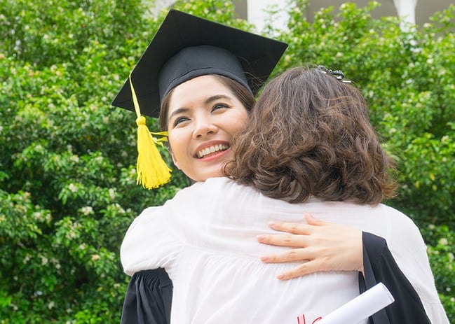 young Asian female college graduate hugging mom