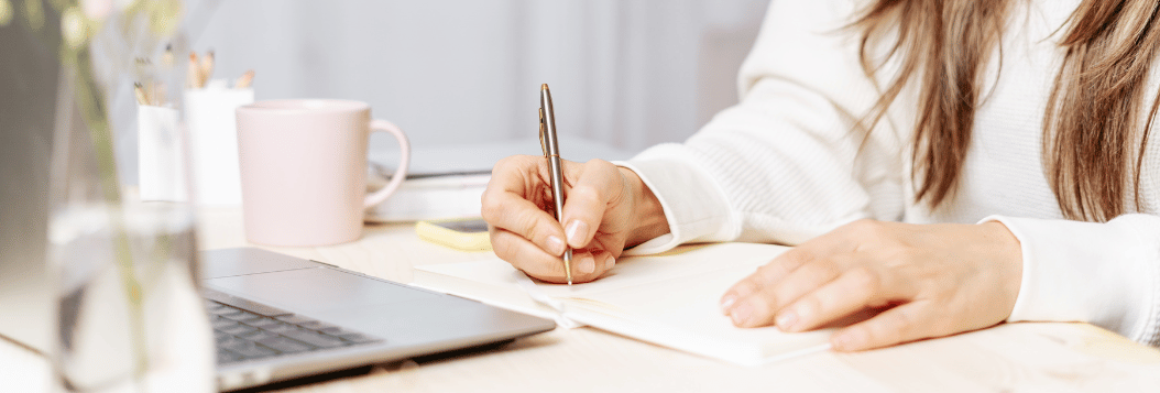 Woman sitting in front of a computer and taking notes