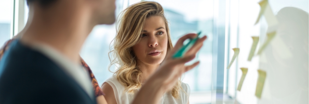 Close up of woman watching intently while they explain something with sticky notes