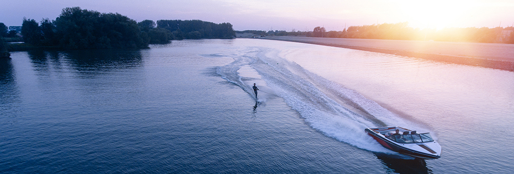 Aerial view of a speed boat pulling a water skier on a large lake.