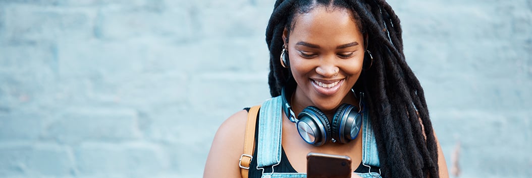 black woman smiling looking at smartphone_1054x357