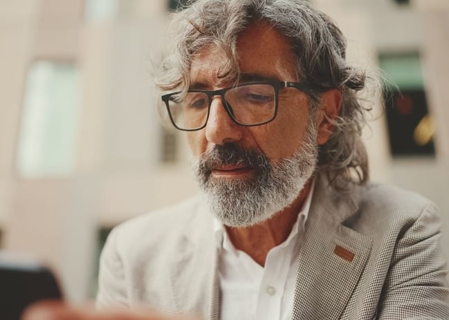 senior man reading information on mobile device