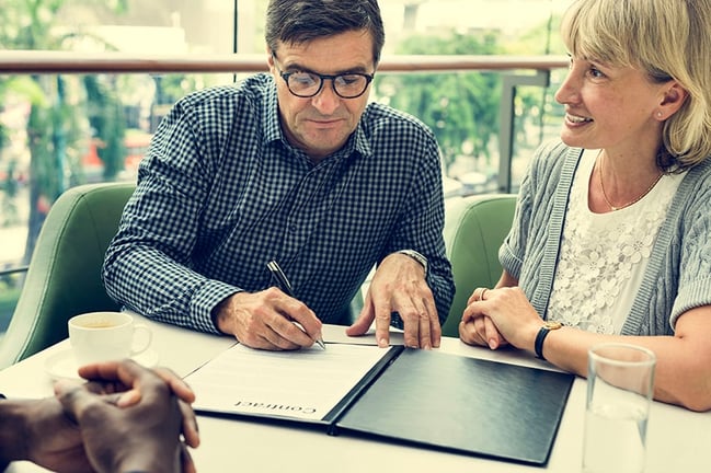 Retired couple discussing financial investments with advisor and reviewing documents