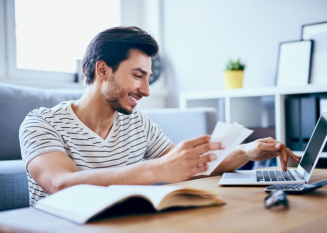 young man paying bills via laptop computer