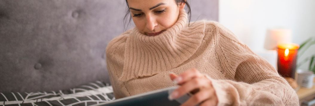 woman reading ebook while relaxing in bed