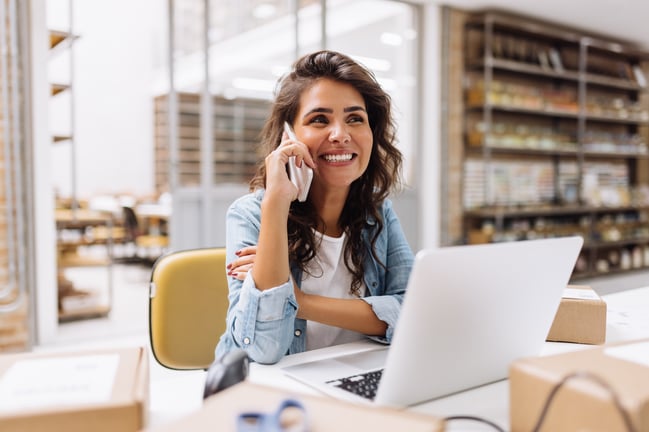 lady at her desk with her laptop open taking a phone call
