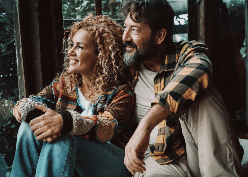 middle aged smiling Hispanic couple looking out of cabin window