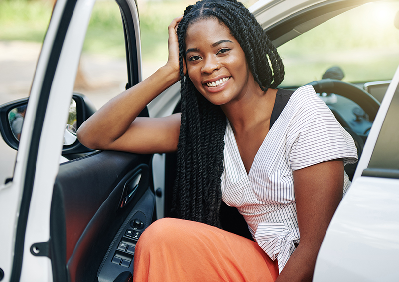 female african-american woman smiling from the front seat of new car