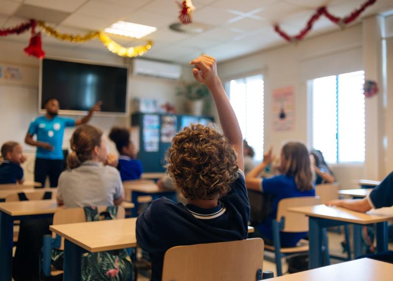 middle school students raising hand in classroom