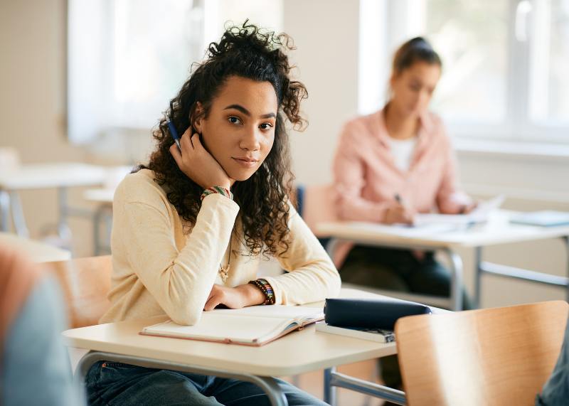 african-american student sitting at desk looking at camera