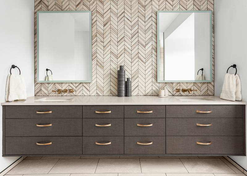 Modern bathroom vanity with two sinks, black elevated cabinets and gold fixtures. 