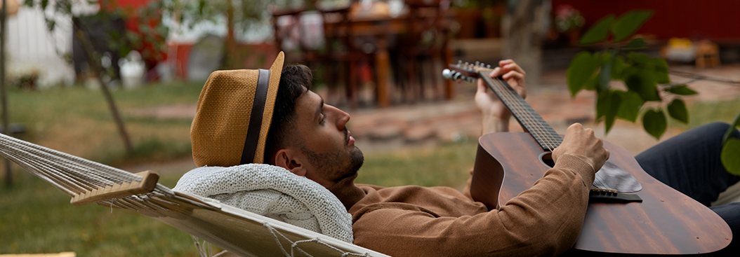man playing guitar in hammock - header