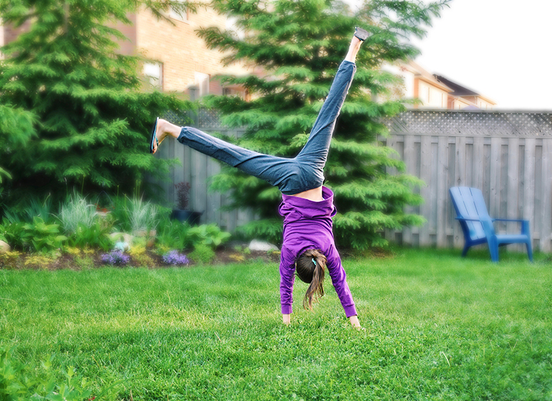 young girl doing cartwheel in backyard