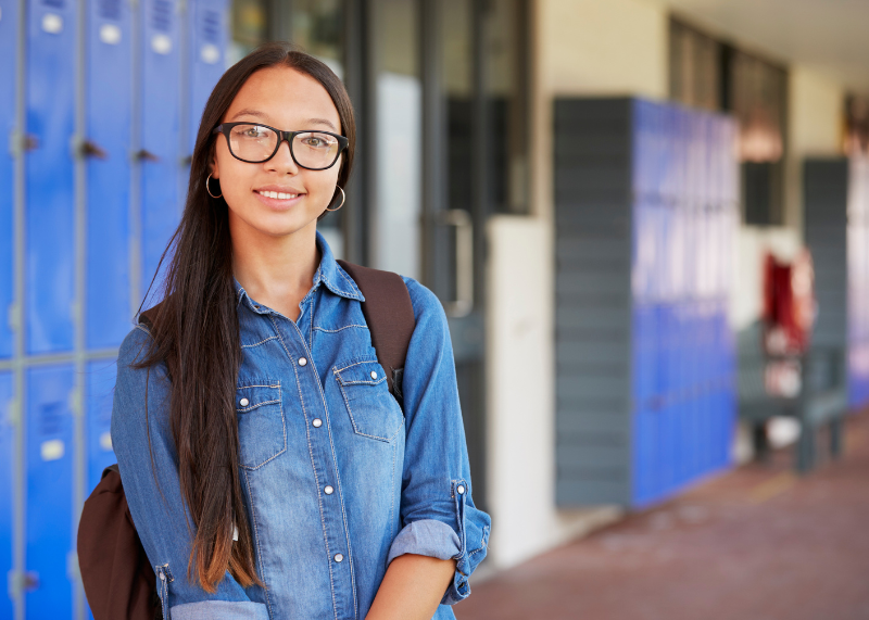 young girl standing in front of bank of school lockers