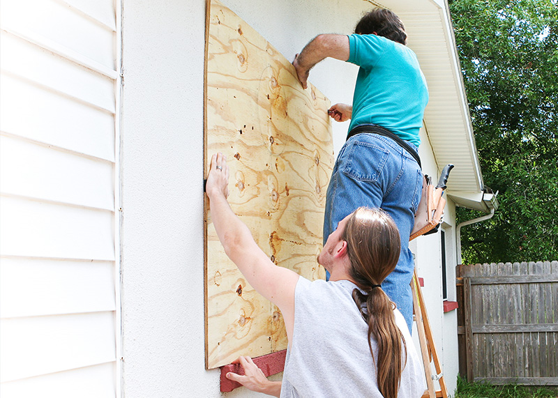 two men nailing plywood to a window