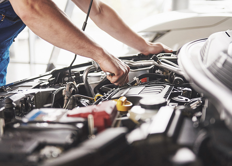 photo of man working under the hood of a car